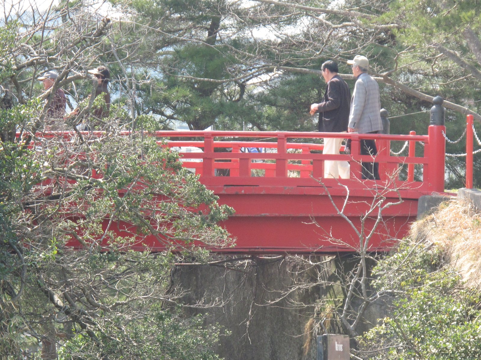 People crossing a short red bridge