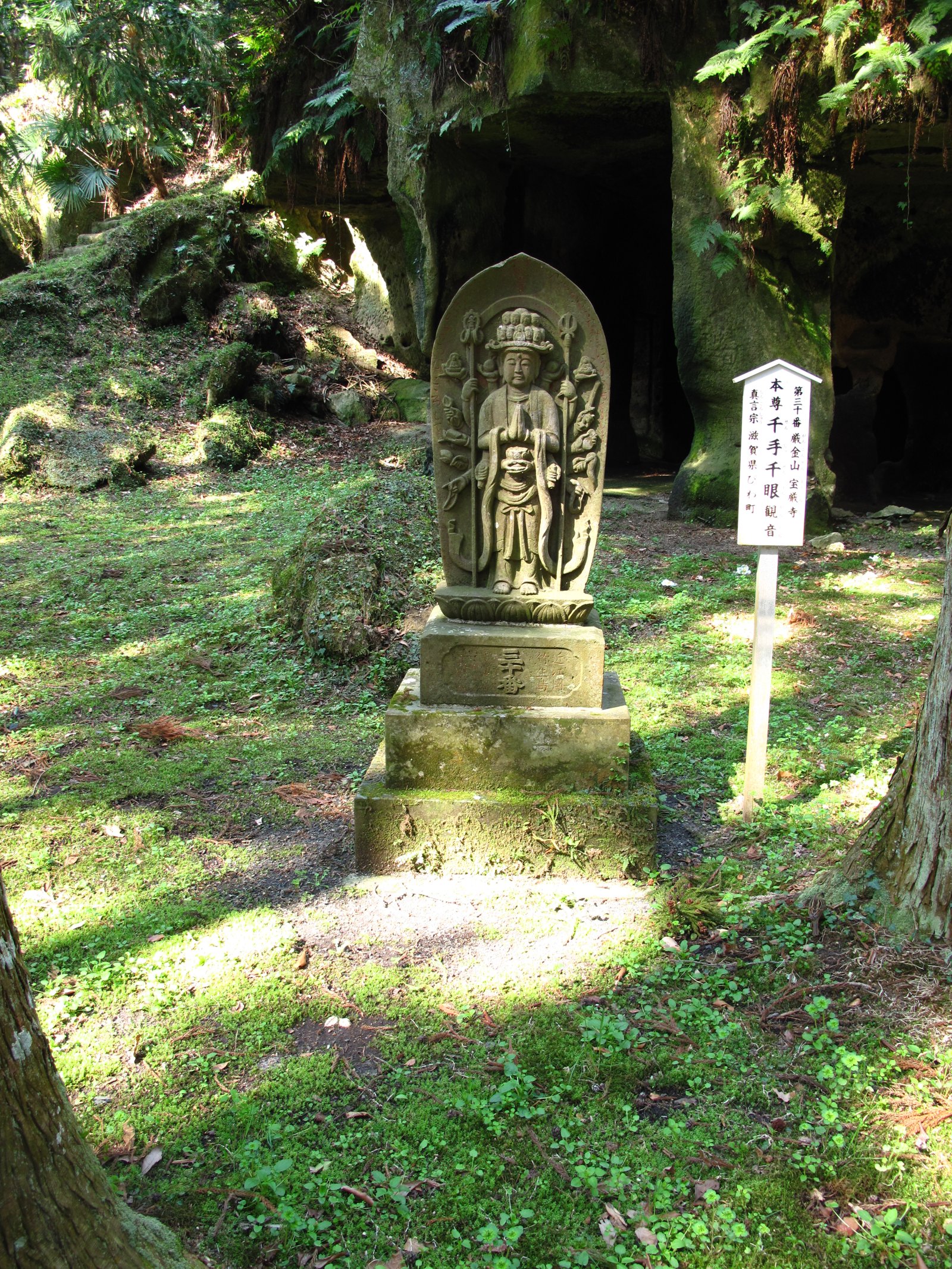A stone statue in front of a cliff with caves