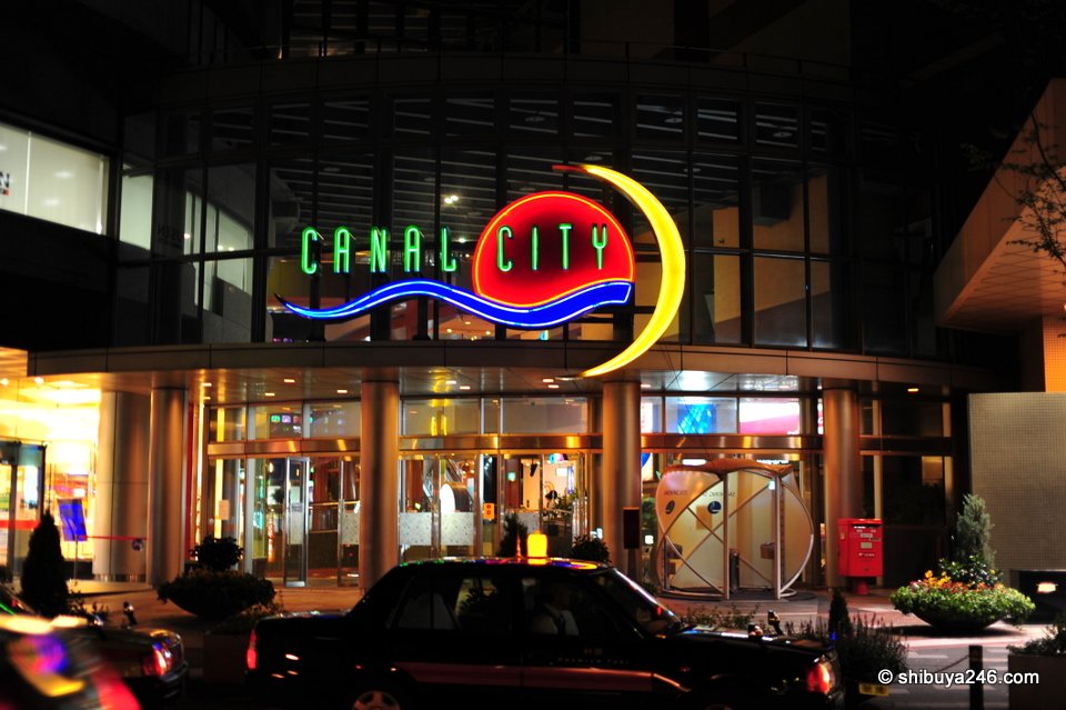 The Canal City sign lit up over an entrance at night