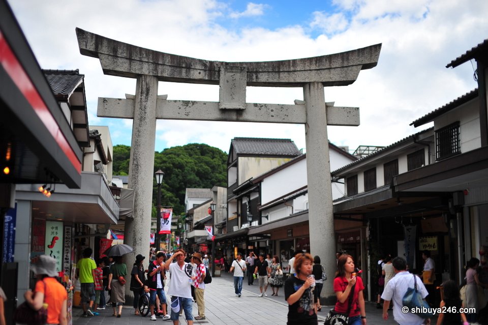 Crowds walking under a large stone torii
