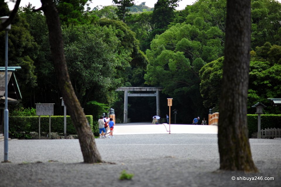 A gravel courtyard with a torii in the distance