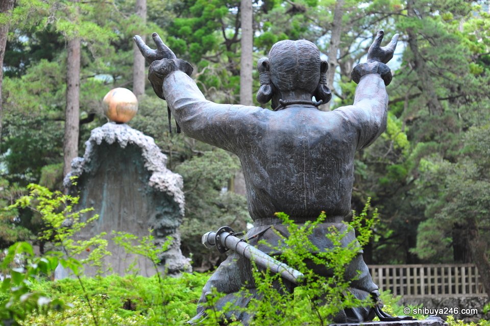 A bronze statue of a figure reaching up towards a golden ball