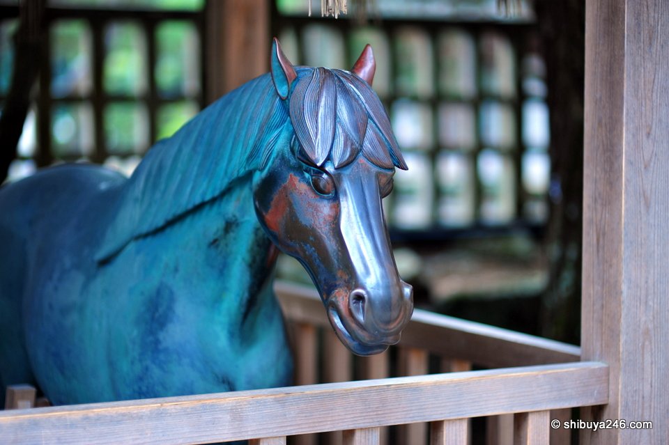 A blue-green bronze horse statue behind a fence