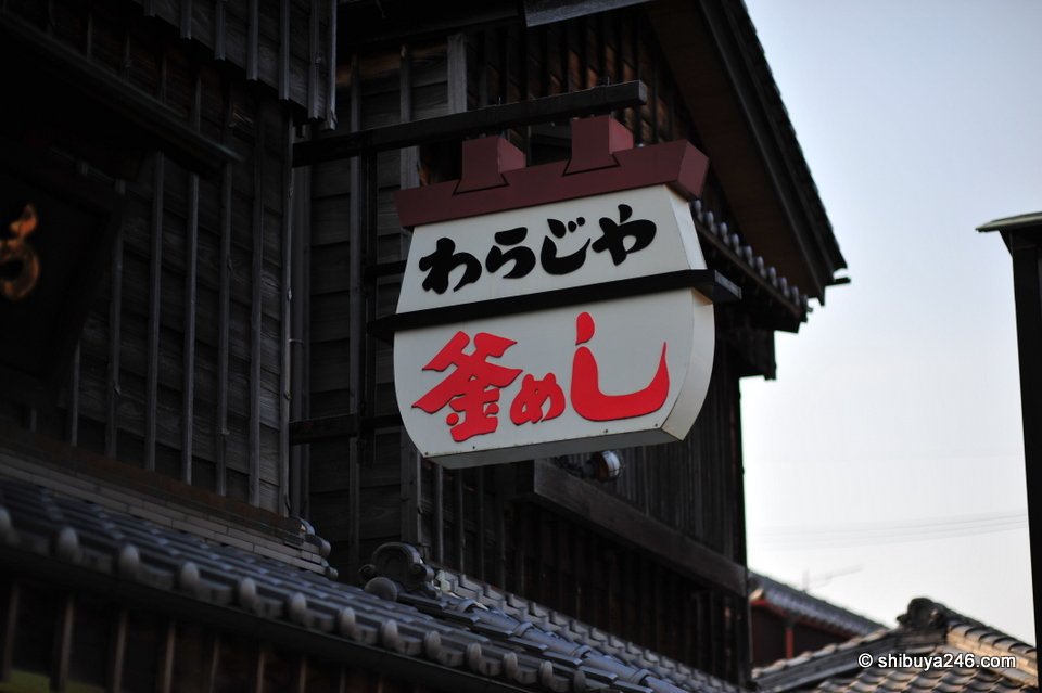 A large wooden sign for a restaurant against the sky