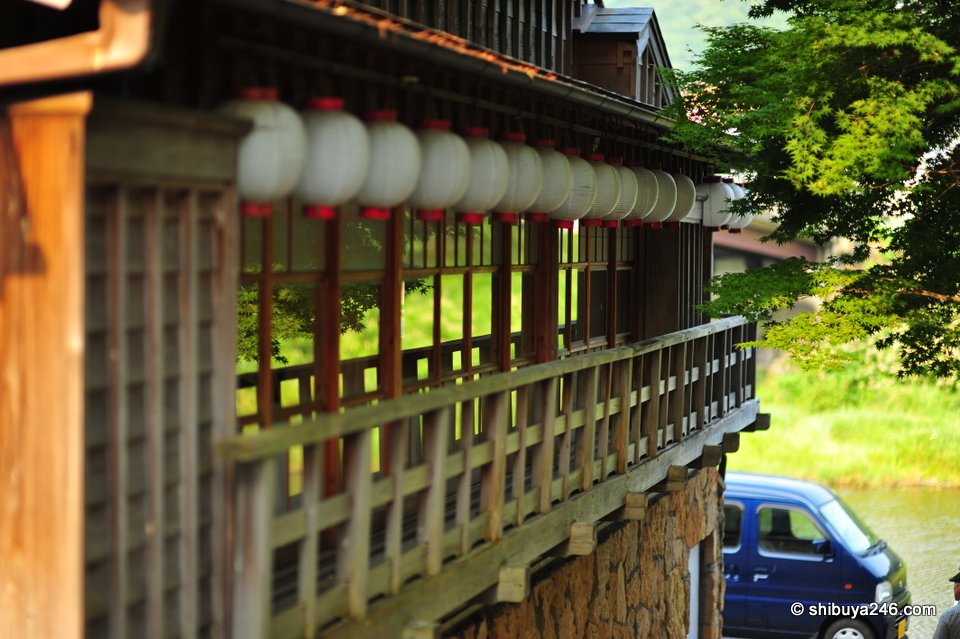 A wooden building with white lanterns hung along the eaves