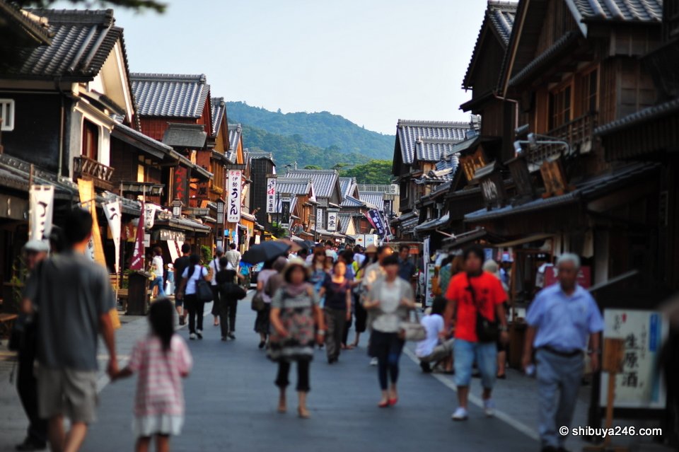 Looking down the long street of wooden buildings with hills behind