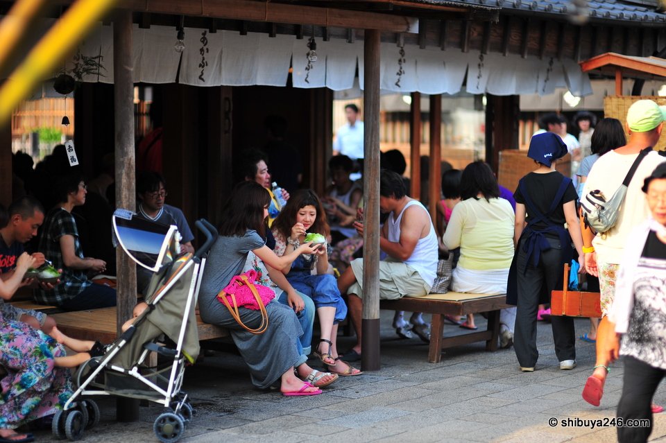 Visitors sitting on benches under a shop's eaves