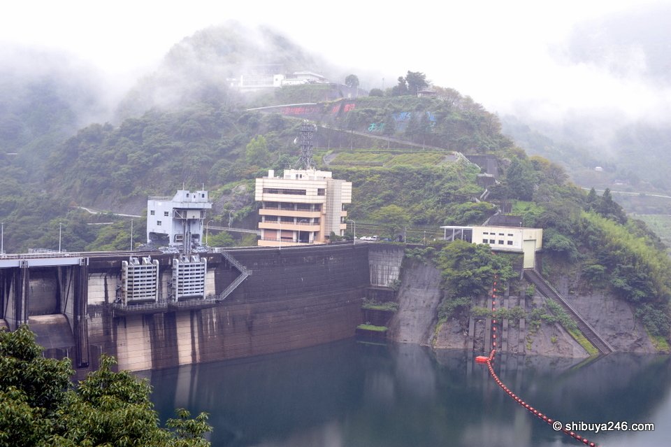A dam across the river with houses on the hillside above