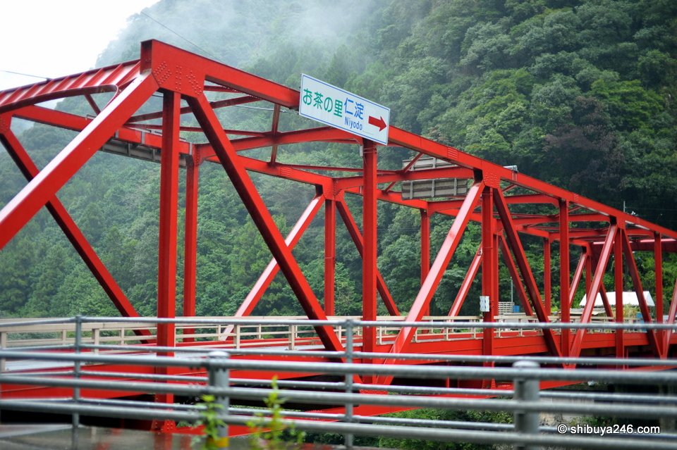 A red steel truss bridge in the rain