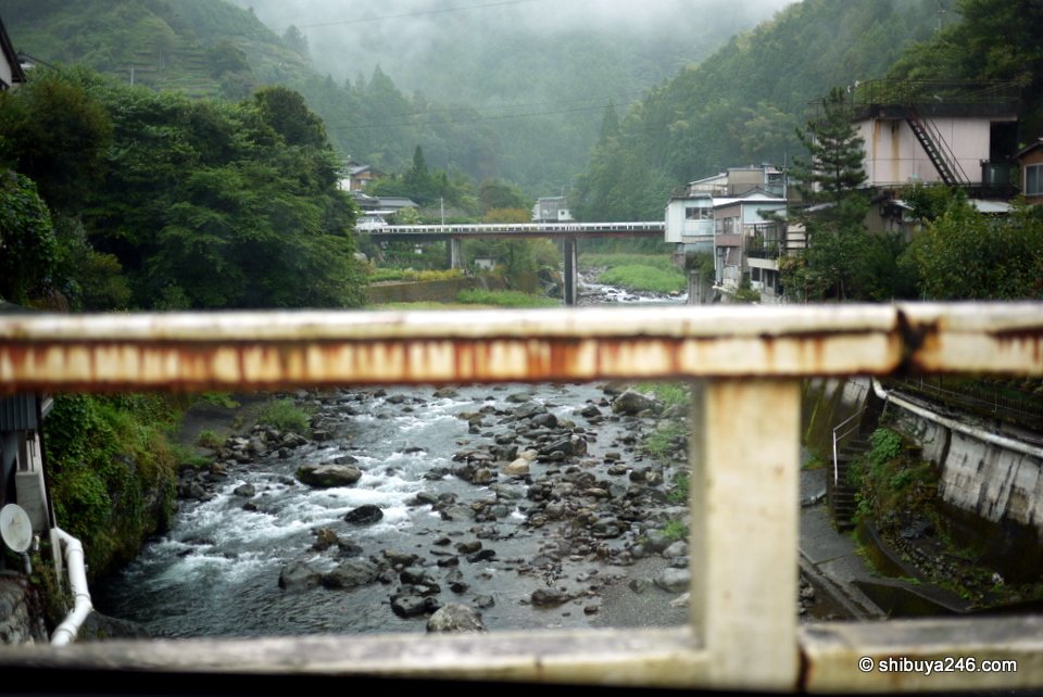 A rocky river seen through a bridge railing