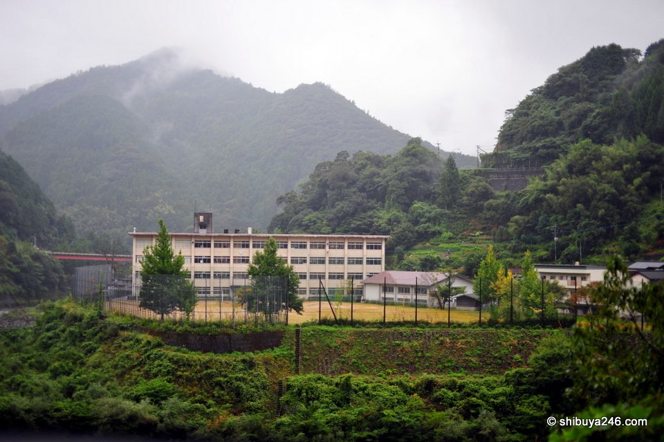 A school building below misty mountains