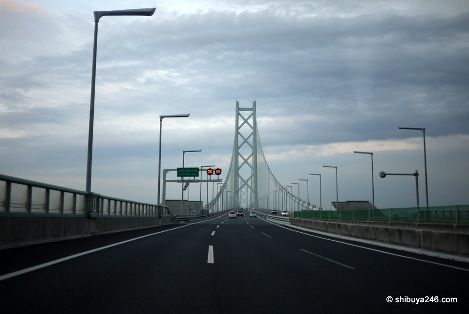A highway leading to a tall suspension bridge tower
