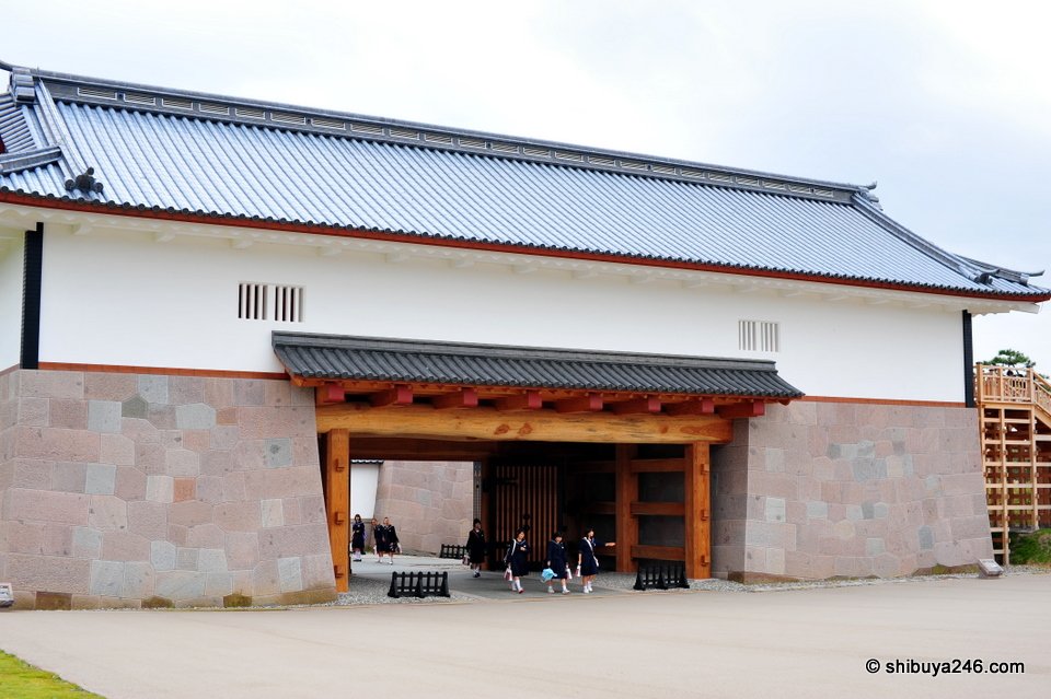A white gatehouse with a wooden gate below