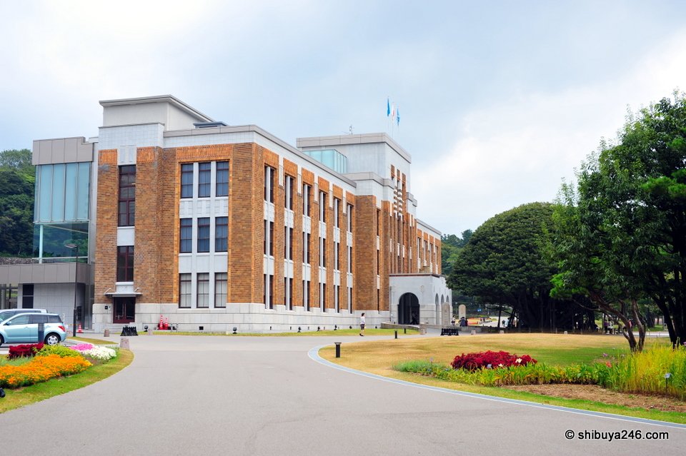 A brick-faced government-style building with a large lawn
