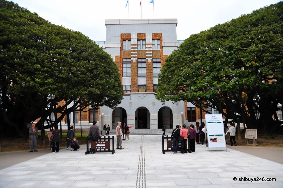 The entrance of a brick-faced building framed by two large trees