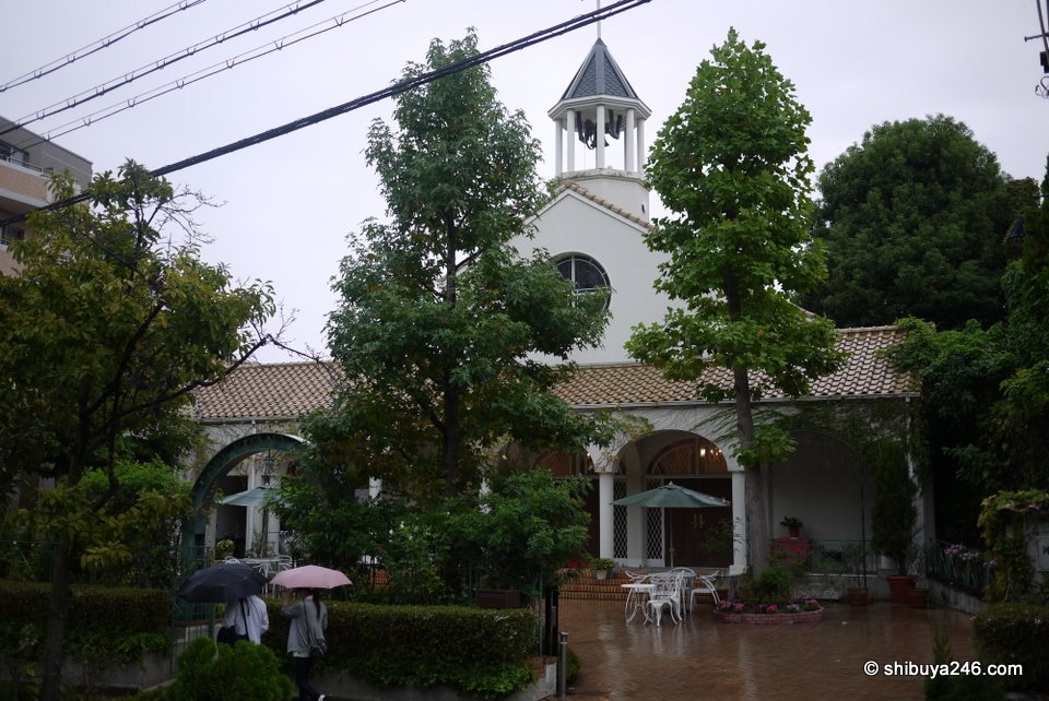 A white building with a small bell tower behind trees