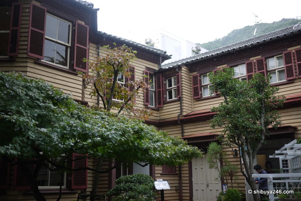 A brown wooden house with bay windows among trees