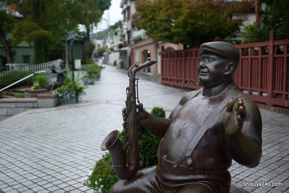 A bronze statue of a man playing a saxophone on a plaza