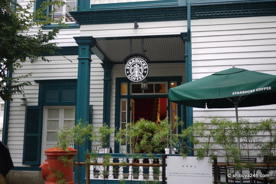 A café in a white wooden Western-style house with green umbrellas
