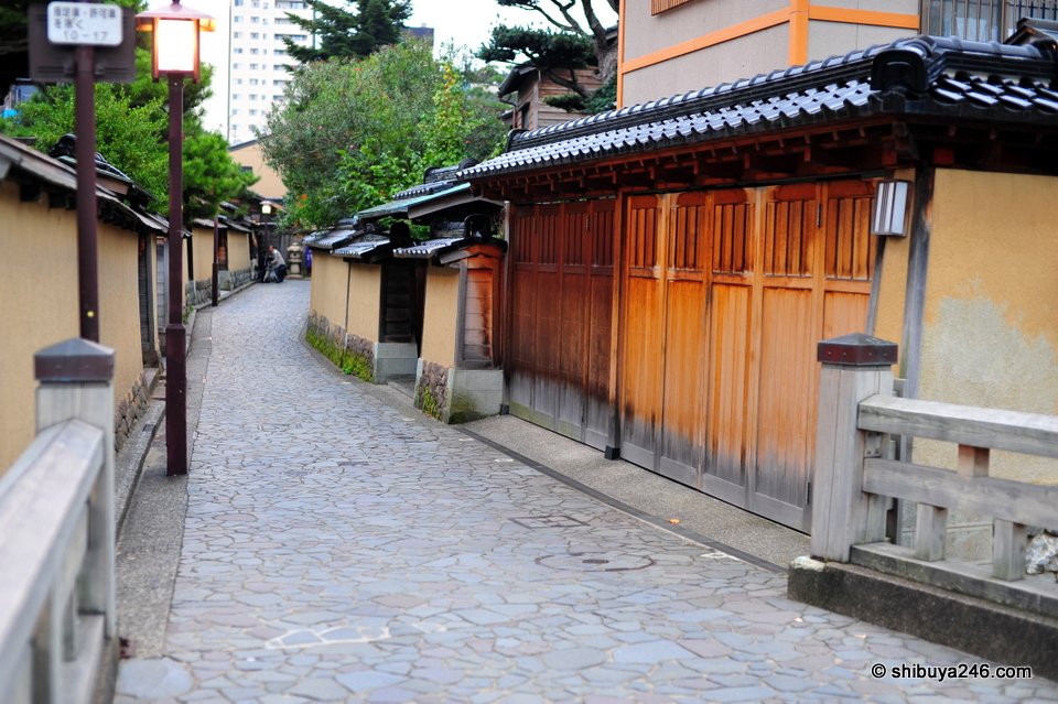 A cobbled lane between earthen walls with a lamp