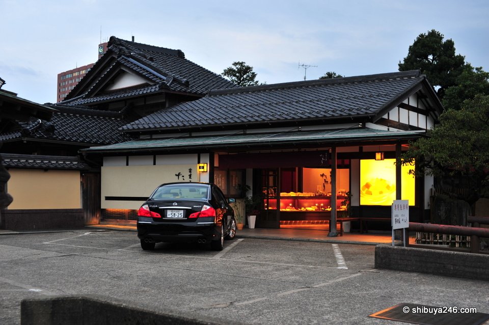 A low wooden building behind a car park