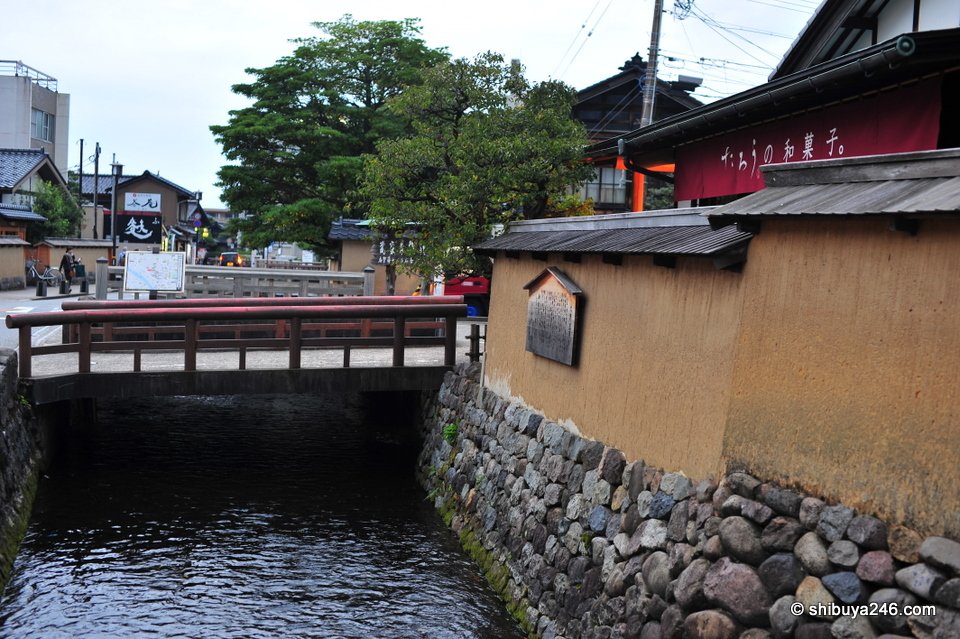 A canal beside earthen walls with a small bridge
