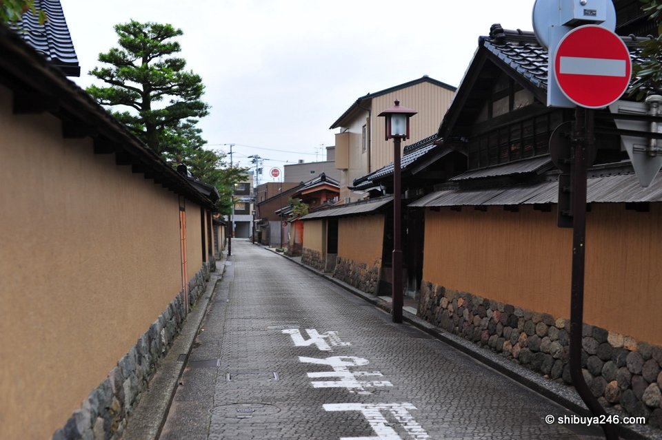 A narrow lane between earthen walls with a no-entry sign