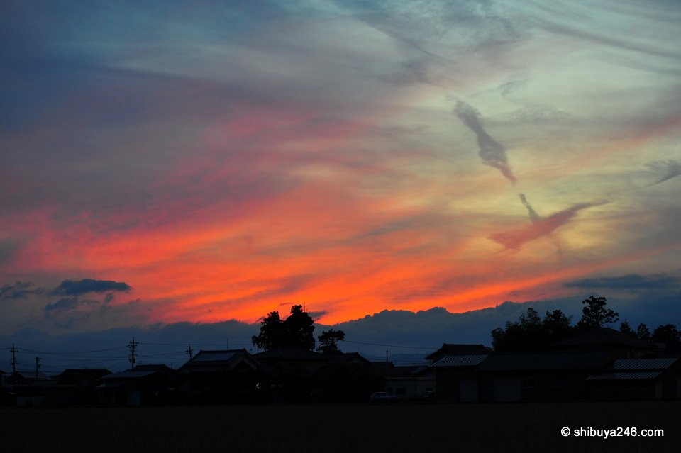 Red and orange cloud with darker cloud shapes above silhouetted trees