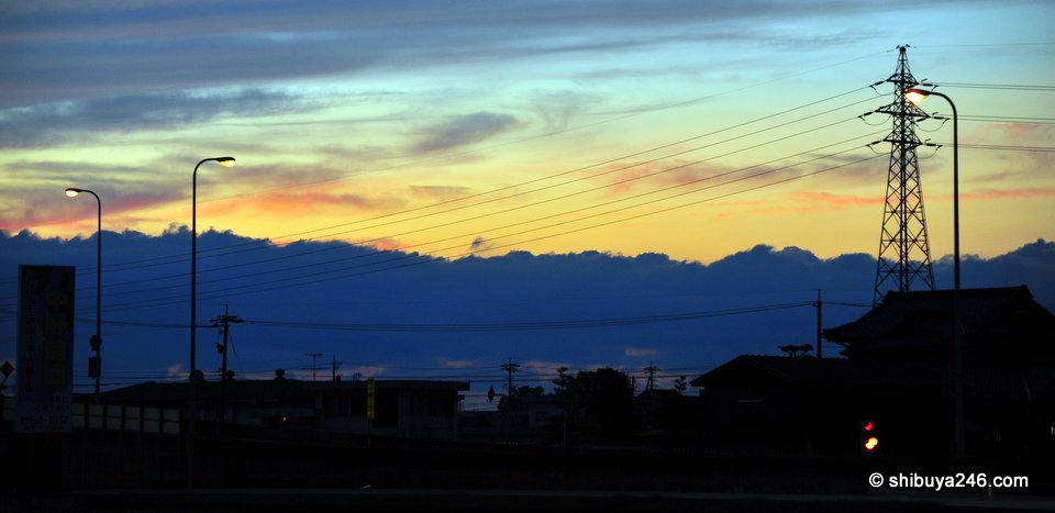 An electricity pylon silhouetted against a blue and yellow evening sky