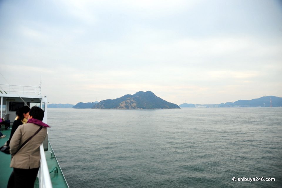 Passengers on deck looking out at a small island