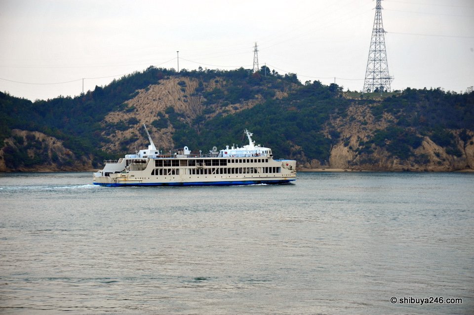 A white ferry passing a wooded headland