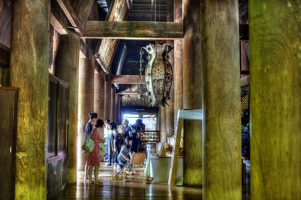 Inside a temple hall with tall wooden pillars and a hanging lantern