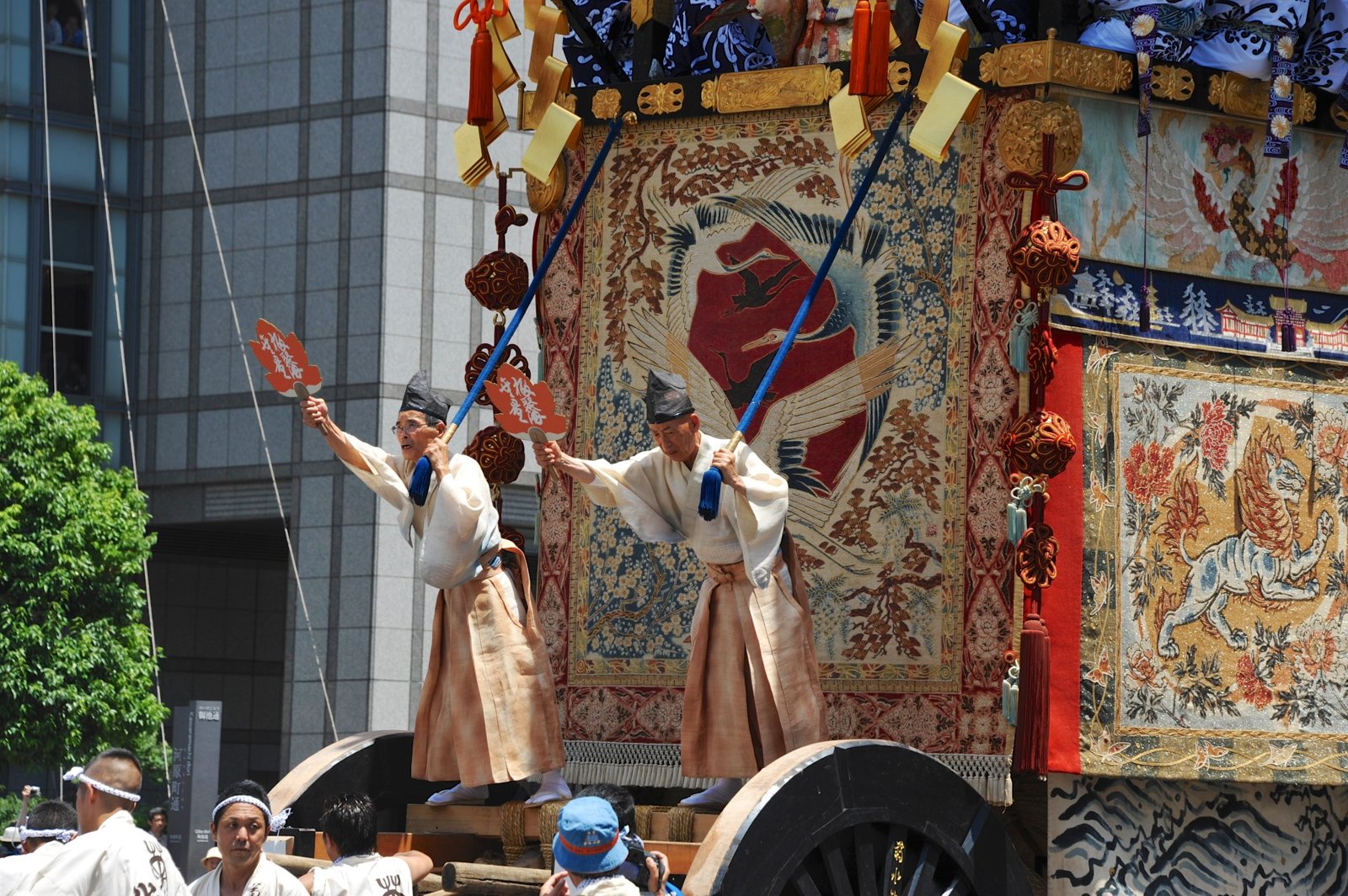 Two men waving fans at the front of a float