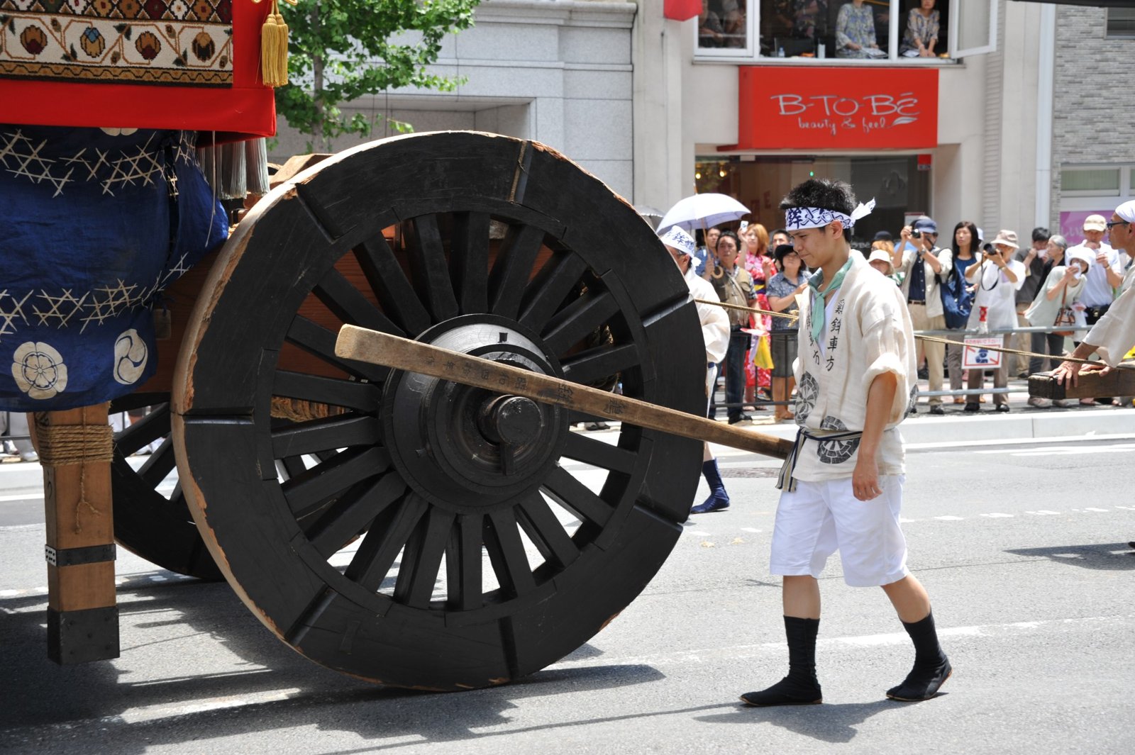 A huge wooden wheel with a man walking beside it