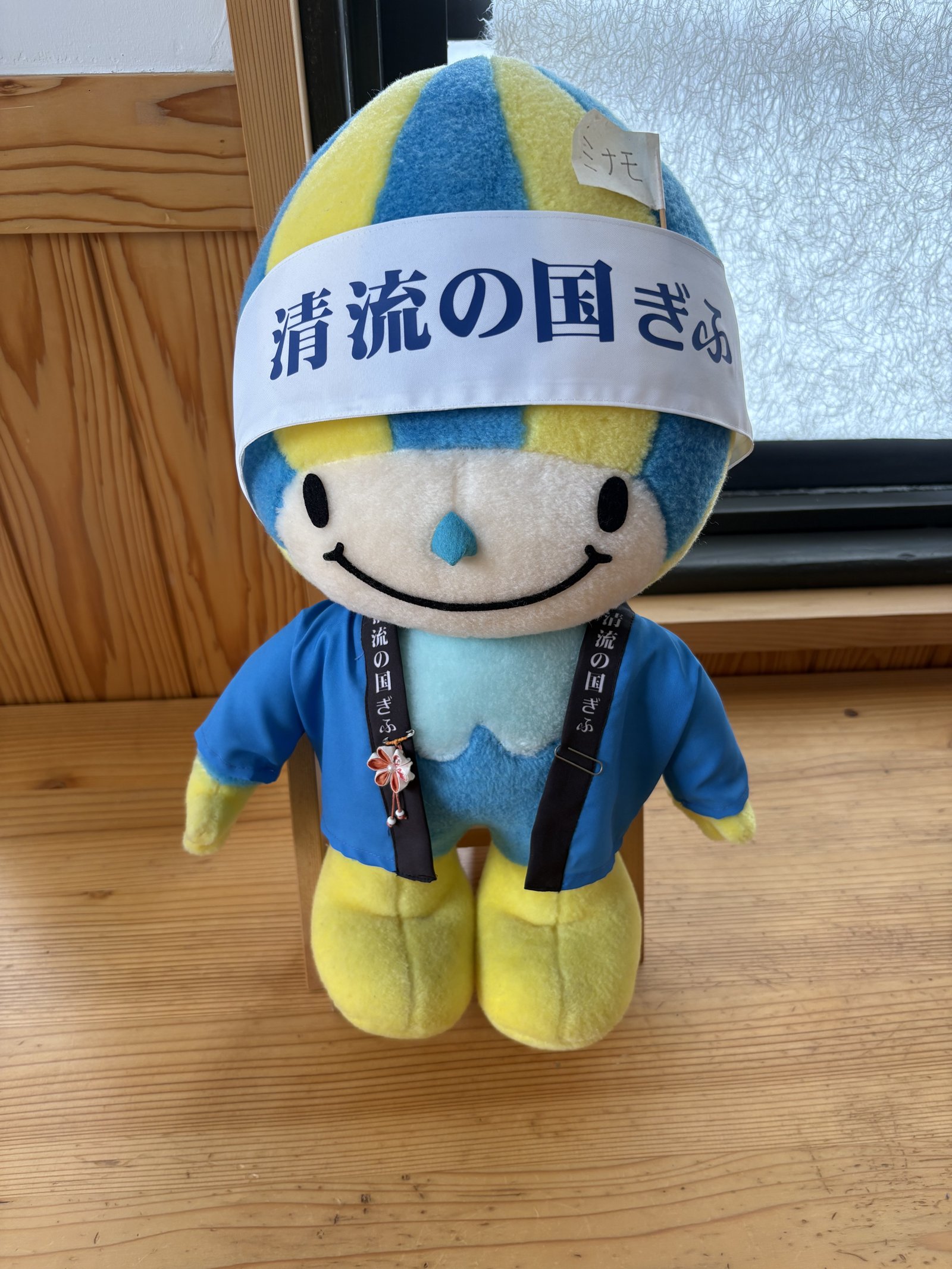 A plush mascot with a blue and yellow head and a 清流の国ぎふ headband